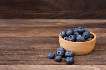 Blueberry fruit in wooden bowl isolated on wood table background.