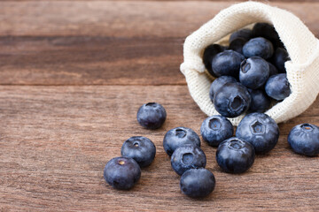 Fresh blueberries fruit in sack bag isolated on wooden table background.