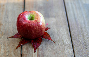 ein Apfel liegt auf einem Holztisch
