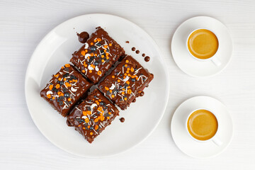 Homemade brownie and two cups of coffee espresso on white wooden table. Top view.