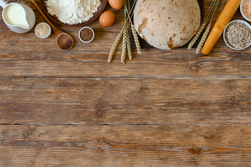 Homemade bread and bakery ingredients on dark rustic wooden background