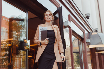Young well dressed business woman with tablet pc leaving building