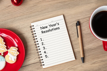 New Year Resolution with notebook, black coffee cup, Christmas cookies and pen on wood table. Xmas, Happy New Year, Goals, To do list, Strategy and Plan concept