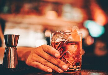 Close up of woman hands holding glass with cocktail in bar