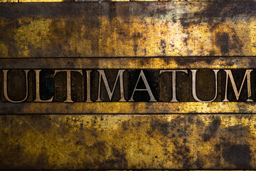 Ultimatum text message on textured grunge copper and vintage gold background