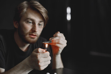 Addict preparing drug dose for injection in dark room