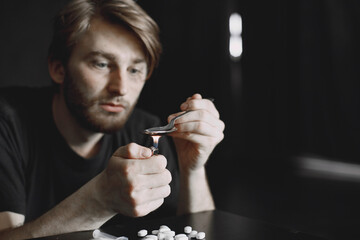 Addict preparing drug dose for injection in dark room