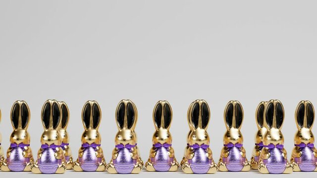 Row of gold and purple Easter bunny figurines on gray background