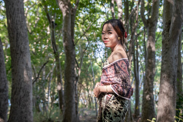 Balinese girl posing in nature and in a forest on Candidasa's offshore islands in Bali, dressed in a traditional costume. 