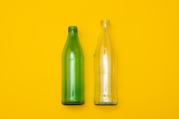 Two empty glass bottle on a yellow background. Eco-friendly packaging, waste recycling concept, glass waste, rubish sort and plastic free lifestyle.