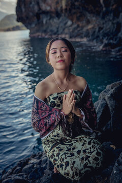 Balinese girl posing in nature and in a on the coast Candidasa's offshore islands in Bali, dressed in a traditional costume. 
