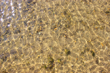 Close-up and top view of shiny transparent yellow sand and stones on the beach with clear water. clear sea, the river reveals the beauty of a natural resting place in the summer under the sun. Has a