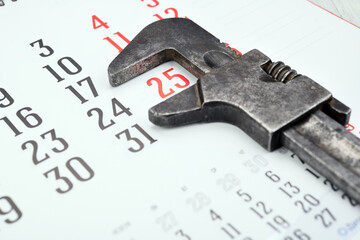 The adjustable wrench lies on the calendar. Planned repair plumbing work. 