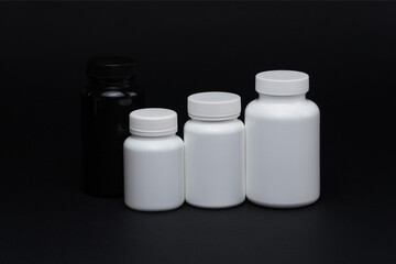 White and black plastic pill jars on a black background. Isolated