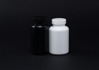 White and black plastic pill jars on a black background. Isolated