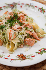 White plate with Christmas decor with grilled salmon, served with herbs, cheese and creamy sauce. Healthy food for the family. Homemade dinner
