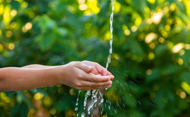 The water flows into the hands of the child. Selective focus.