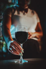 waiter hold red wine into a glass in cafe or bar