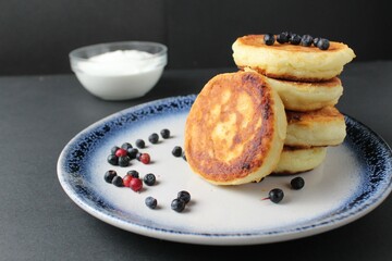 breakfast pancakes cheesecakes are stacked slide on a plate with blueberries blueberries cherries. Traditional breakfast Russian Slavic in the background is egg flour. Cooking breakfast