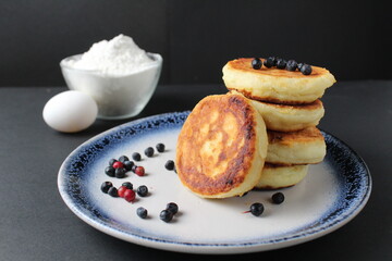 breakfast pancakes cheesecakes are stacked slide on a plate with blueberries blueberries cherries. Traditional breakfast Russian Slavic in the background is egg flour. Cooking breakfast