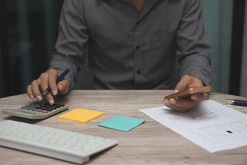 business man working on table at office. man use calculator to calculate with business graph or chart and using smartphone to analysis statistics and strategy for investment success target.