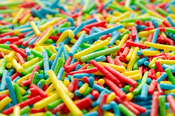 Sugar paste for decoration, background, top view. Rainbow sprinkle for confectionery. Colorful confetti, background, top view. Pile of confectionery sprinkles, top view. Confectionery decor.