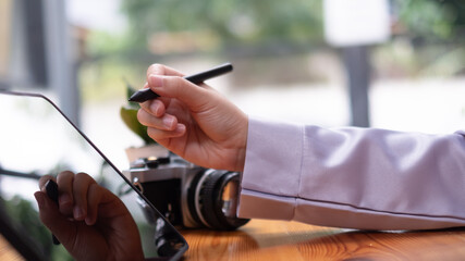 Asian woman hand holding pen stylus writing on digital tablet computer. close up