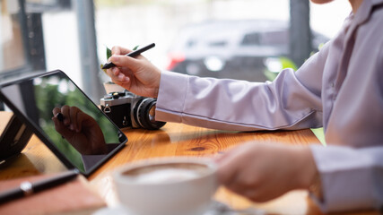 Asian woman hand holding pen stylus writing on digital tablet computer. close up