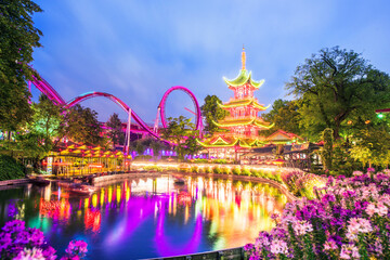 breathtaking magical landscape in Tivoli Gardens in the evening with rides in the illuminations. Copenhagen, Denmark. Exotic amazing places. Popular tourist atraction. - obrazy, fototapety, plakaty