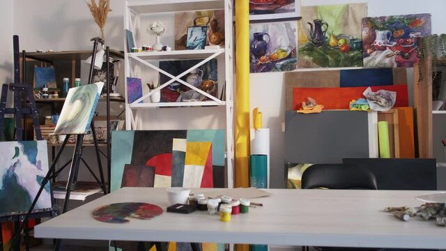 Art workshop interior. Painting class. Creative lifestyle. Cozy empty workplace artist studio room in daylight with painter drawing supplies table palette paints easel artwork.