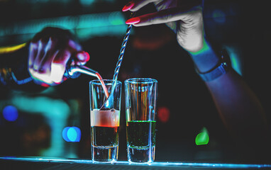 bartender hand making collection of colorful shots. two cocktails at the bar counter