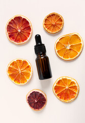 essential fruit acid bottle with decorative orange slices on light beige background. top view. beauty treatment concept