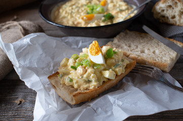Egg salad sandwich on roasted baguette bread served on rustic wooden table 