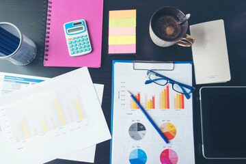 Office laptop business financial document chart and graph on wooden table with coffee cup. Flat lay...