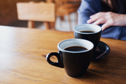 Closeup image of a woman and two cups of coffee on wooden table
