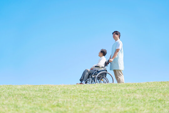 高齢者の車椅子を押す介護士