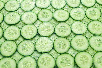 Fresh green slices of cucumber as background.