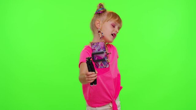 Cheerful funny little teen girl kid dancing at camera filming video using phone at home on chroma key background. Schoolgirl child creating her trendy content on a mobile app to share on social media