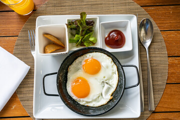 Breakfast - Sunny side up fried eggs with tomato sauce and potato wedges.