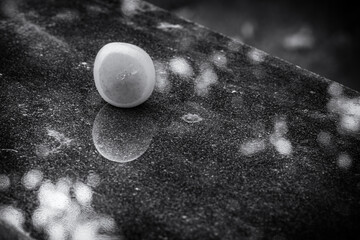 black and white picure of ripe yellow plum on shiny polished granite table