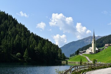 Lago di Valdurna in AltoAdige cielo serene e riflessi sulla superficie, chiesa tipica con campanile appuntito