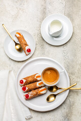 Breakfast with Italian pastry cannoli with ricotta cream. Coffee cup,  on white stone background. Copy space, vertical image.