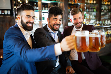 Team of colleagues socializing at the bar and drinking beers
