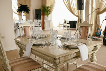 Place setting with menu and plates  at elegant shabby chic table. Beautiful table set for an event party or wedding reception . Restaurant interior.