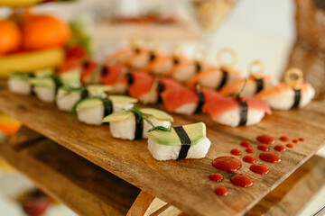 Set of different kinds of sushi rolls with salmon, shrimp and vegetables on wooden plate