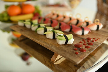 Set of various kinds of sushi on a wooden plate. large set with sushi and rolls. Sushi and rolls, fish, vegetables  with wasabi and ginger. 