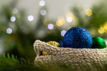 Christmas concept. A blue Christmas ball in a light crocheted basket on a blurry shiny background.