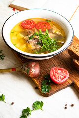 fish soup with carp, potatoes, parsley, tomato in enamel bowl stands on a board