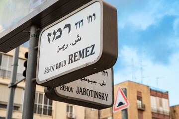 Obraz premium Urban city navigation street name sign, crossroad corner Remez and Jabotinsky in Tel Aviv, Israel