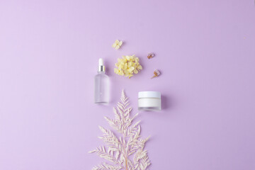 Cosmetic skin care products with flowers on rose background. Flat lay, copy space